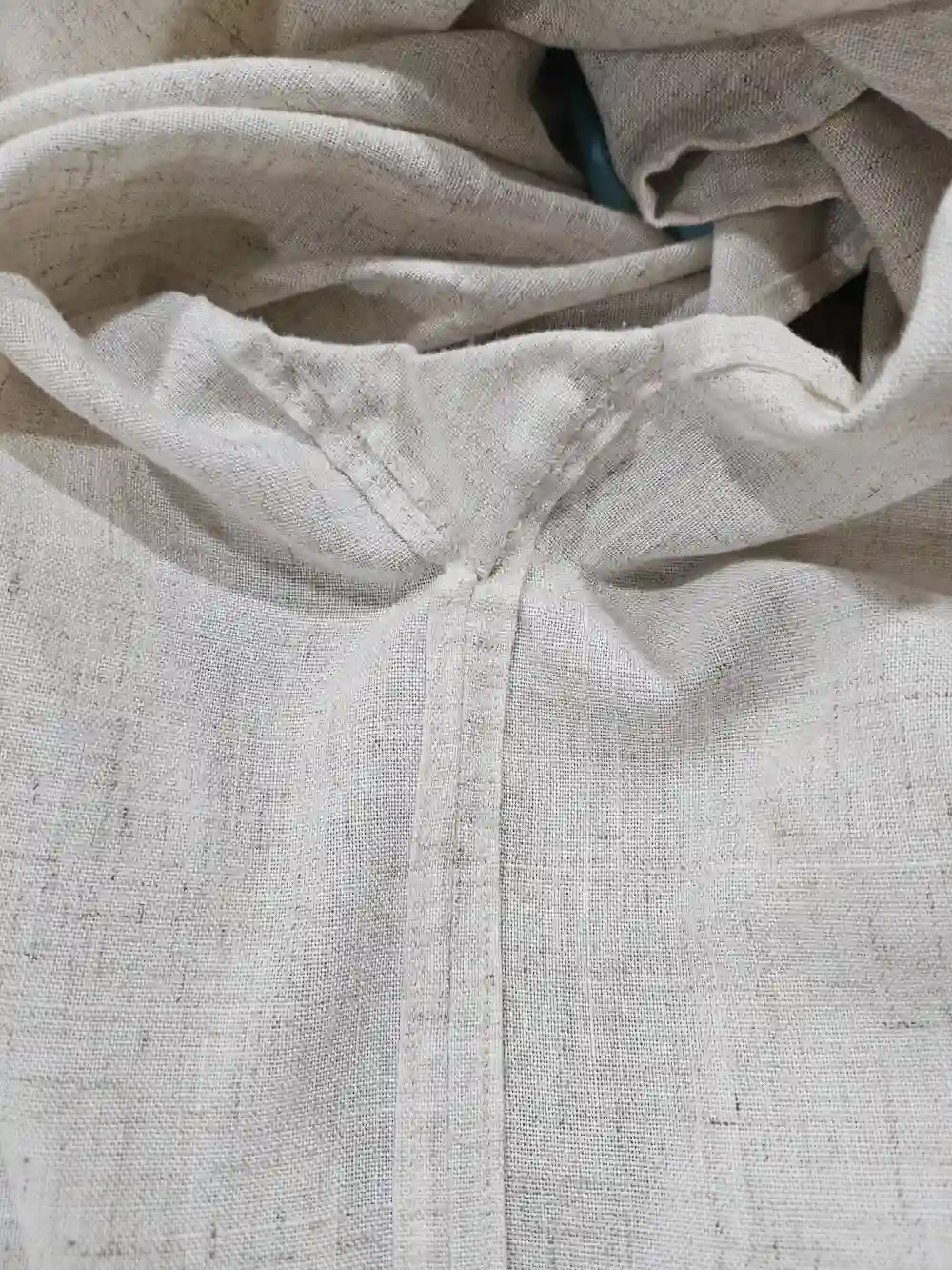The inside of the side seam of the linen shirt, showing small handstitching on the gusset.
