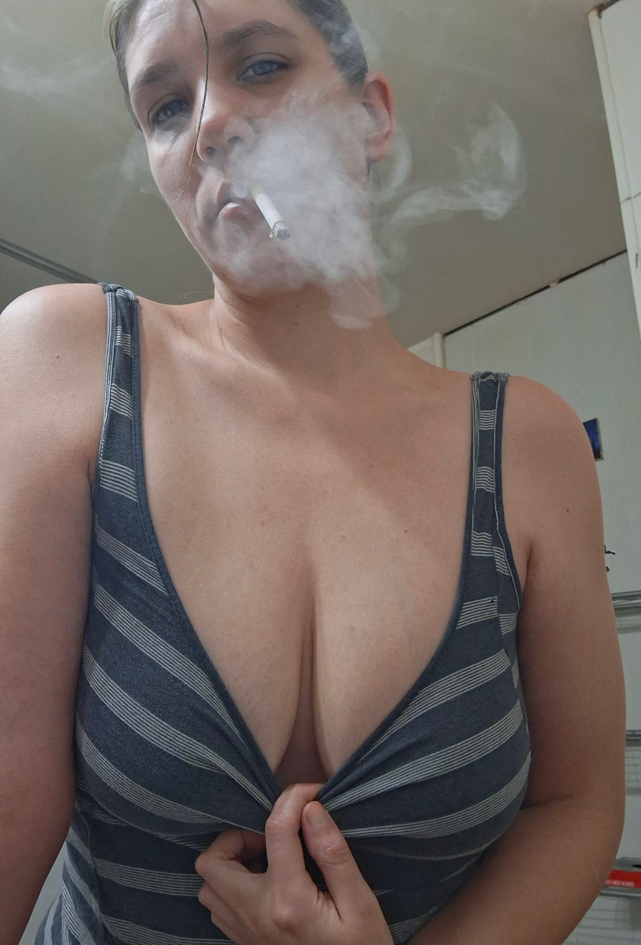 Valerie Rayne pulls her tank top down while exhaling an abundance of smoke from her cork-filtered cigarette.