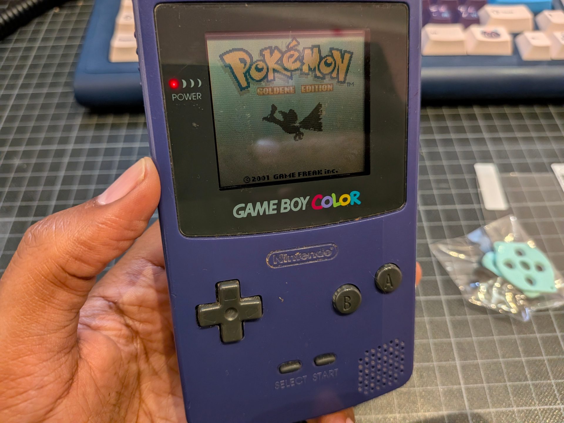 Gameboy Color turned on showing the start screen of Pokemon Gold