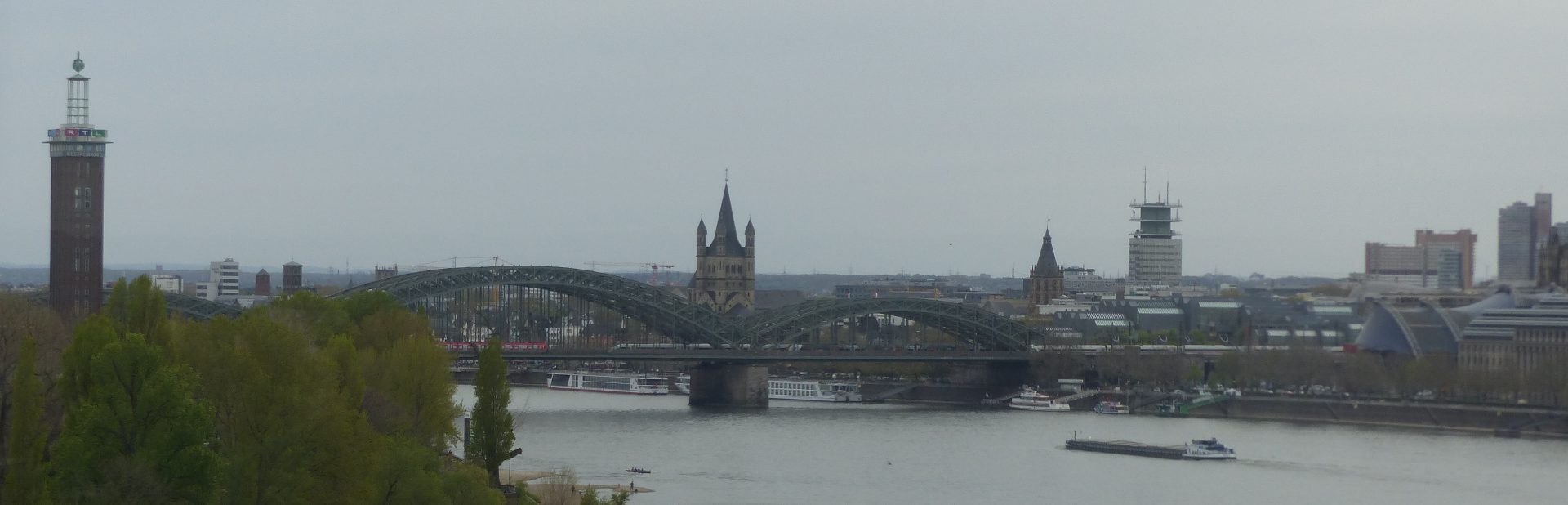 Blick auf den Rhein mit Hohenzollernbrücke und das rechts- und linksrheinische Ufer der Stadt mit RTL-Turm, Hohenzollernbrücke, Groß St. Martin, dem Rathausturm und dem Musical Dome.