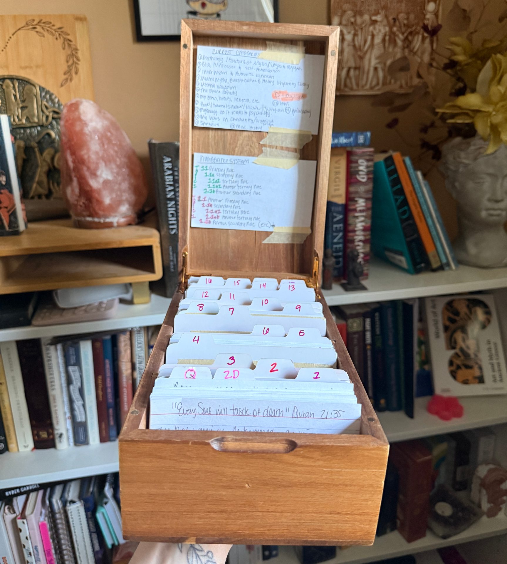 I am holding my old Zettelkasten system in front of my bookshelf: this was a recipe box that held all my individual notes on index cards.