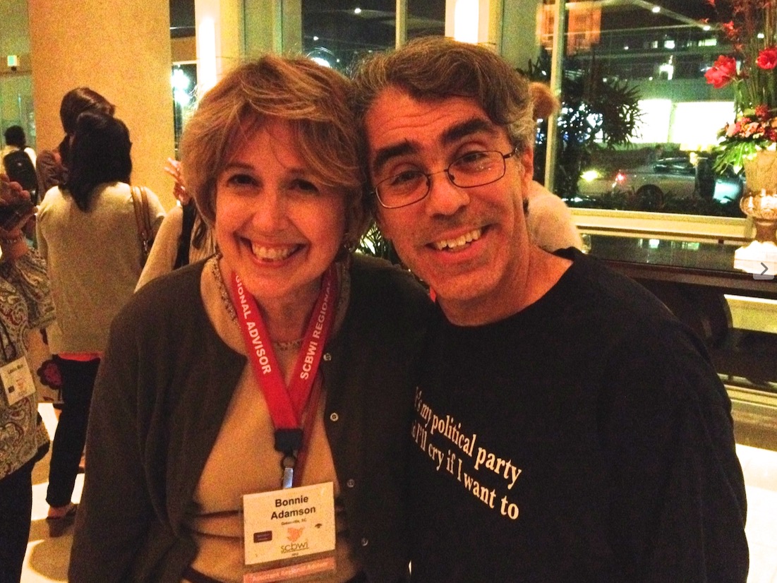 Two smiling people, one wearing a red lanyard and conference badge.