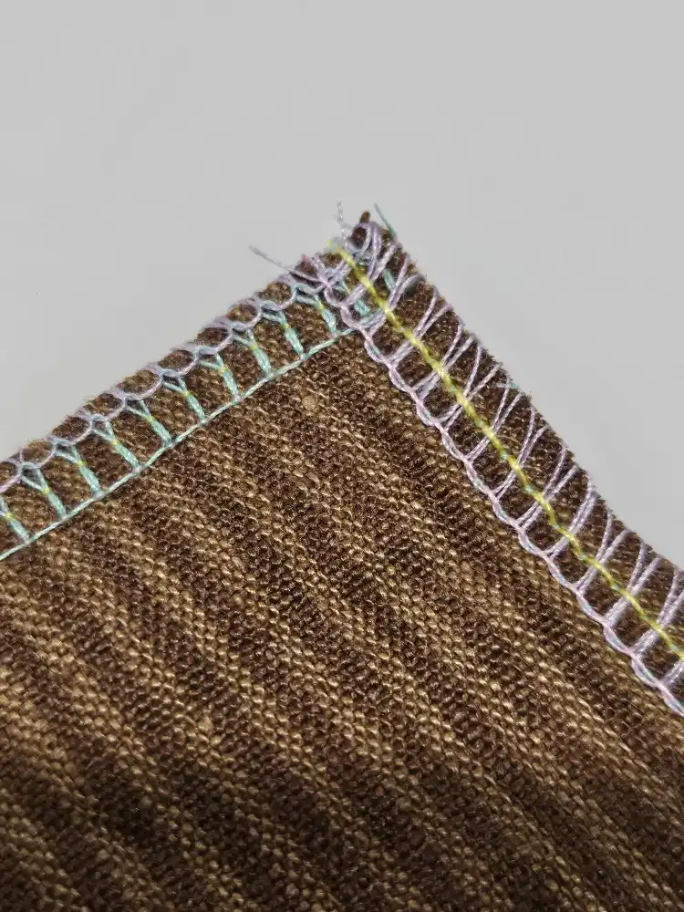 A corner of the striped fabric shows pastel overlock seams.