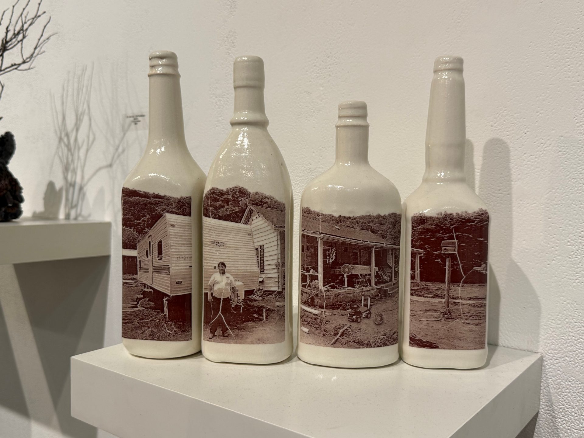 a collection of ceramic bottles with a photograph printed across them featuring a man in outside his trailer home.