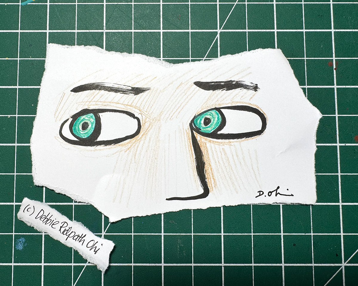 Illustration of a pair of green eyes, thick black eyebrows, and a long black nose drawn on a torn piece of white paper. The paper rests on a green self-healing cutting mat with a white grid. A small torn strip with the artist's name lies beside it: Debbie Ridpath Ohi.