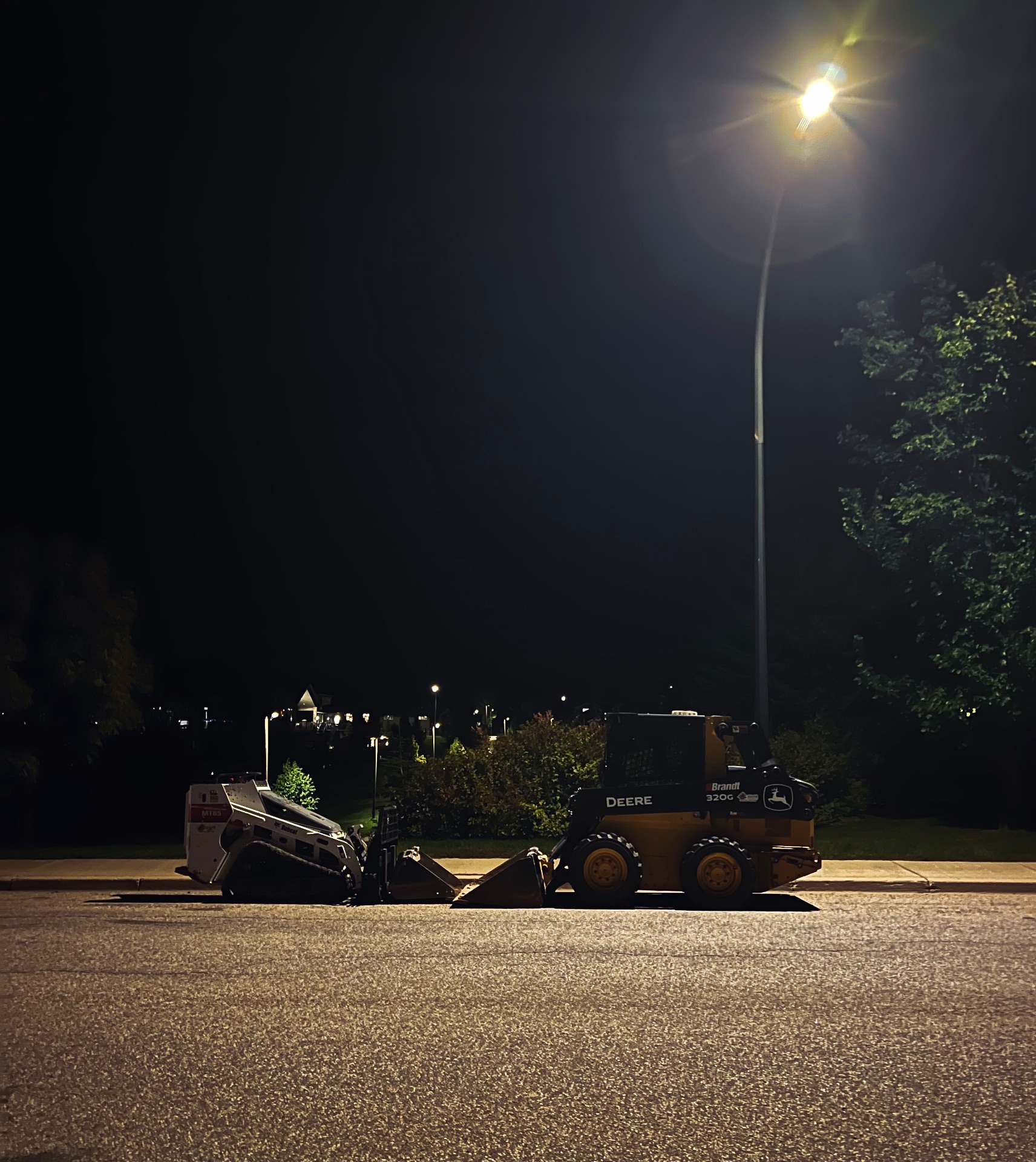 Two machines sit under a lamp post at night facing each other