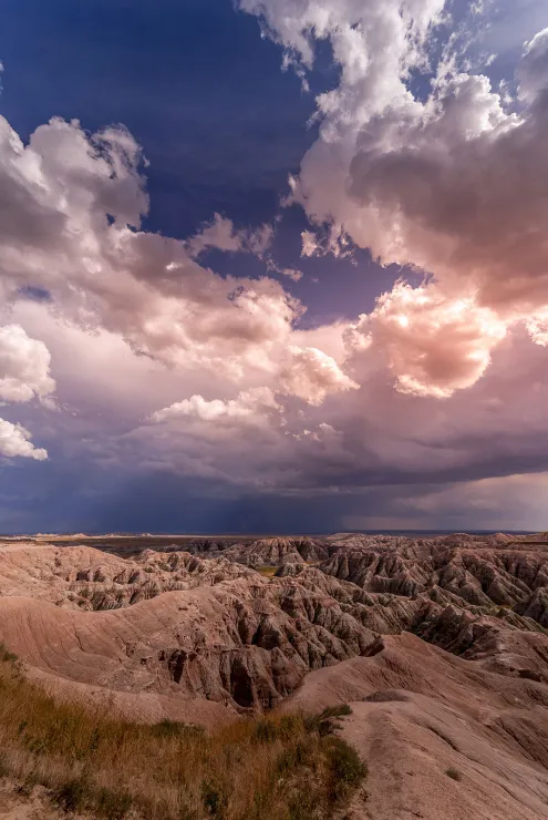 As advertised, sharply eroded buttes form a twisted maze of canyons under a sky filled with pillowy clouds. Although it's still sunny in the foreground, you can see that way off in the distance there's some rain falling.