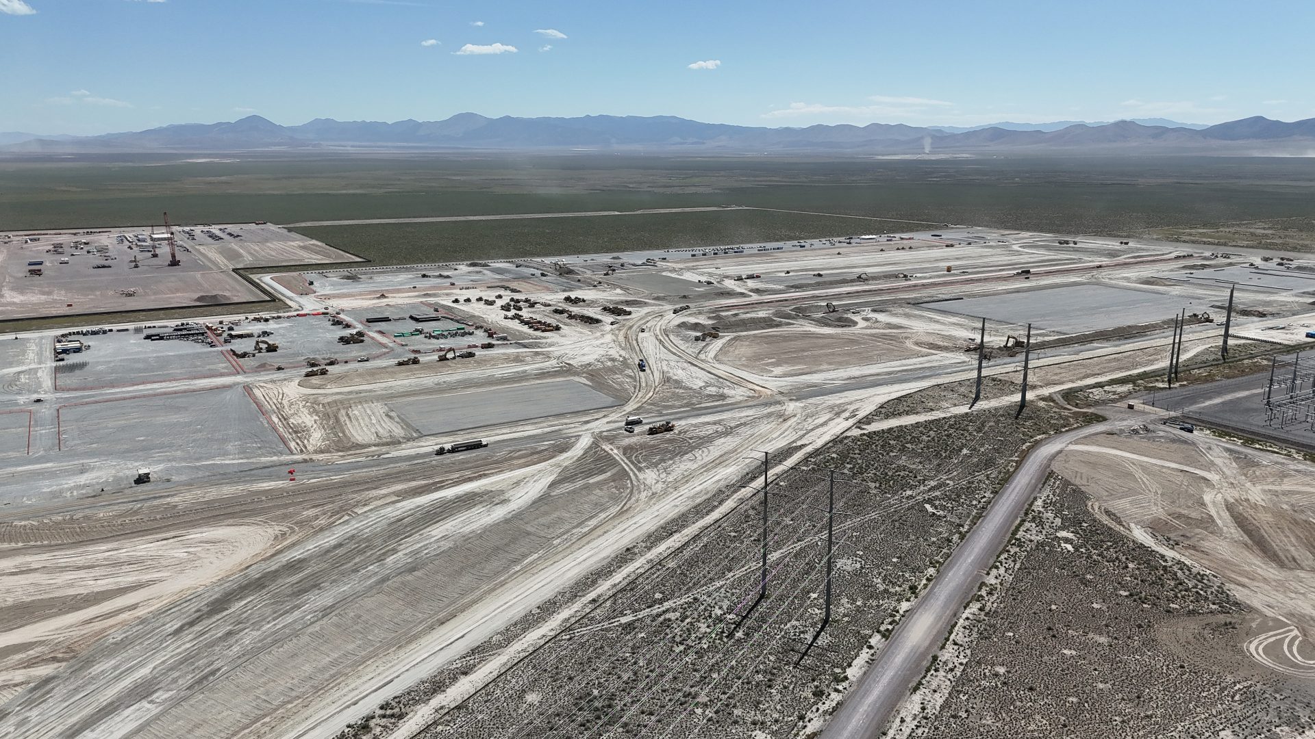 An active construction site. The ground is being leveled, and there appear to be some cranes set up in the background.