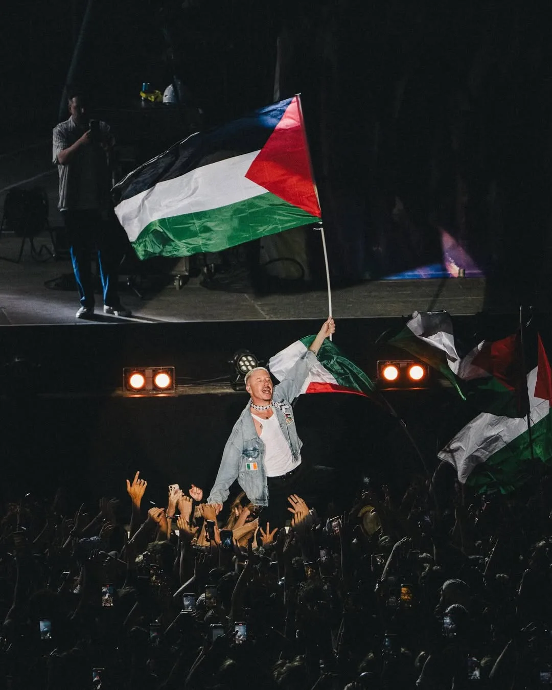 El rapero Macklemore ondeando una bandera palestina en un concierto en julio de 2025