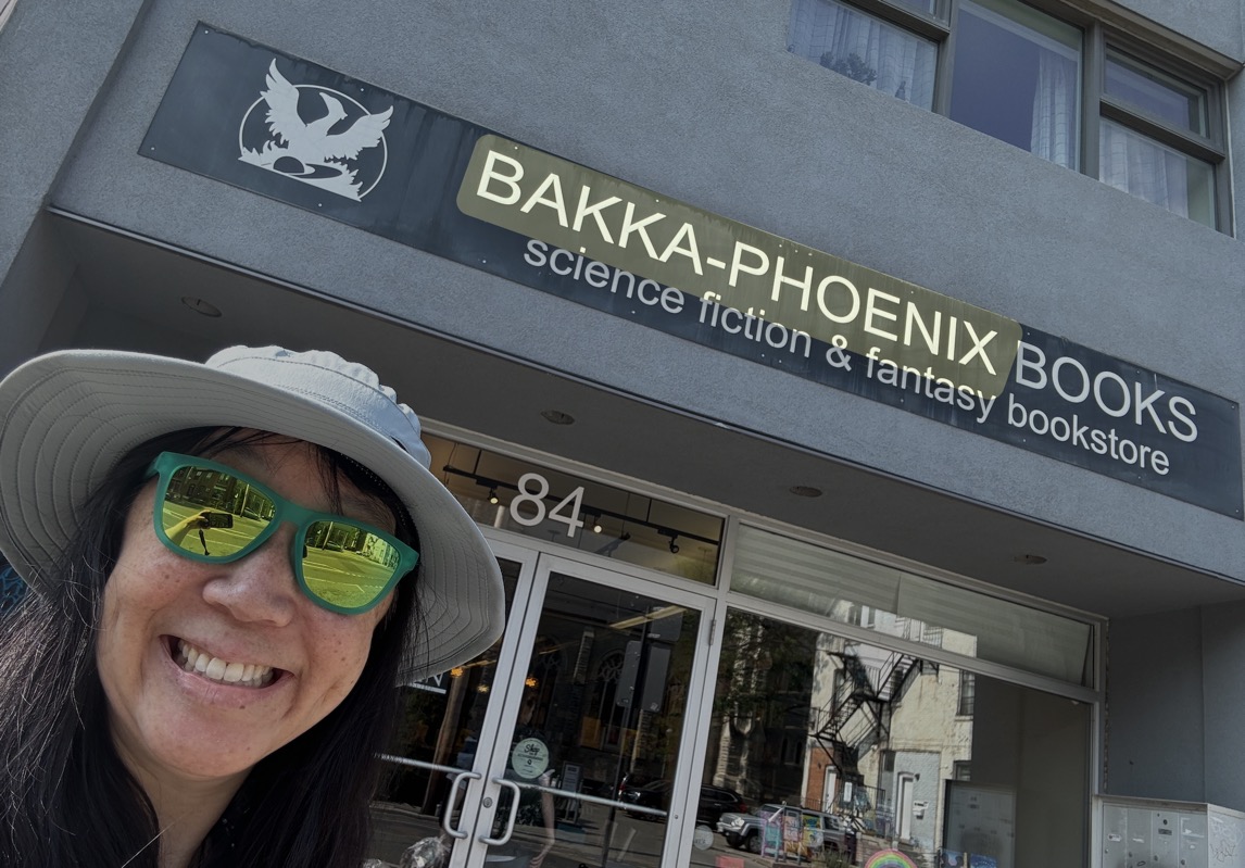 Smiling person doing selfie in front of Bakka-Phoenix Books: Science Fiction & Fantasy Bookstore.