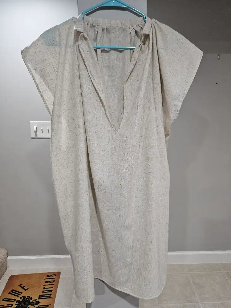 A sleeveless linen shirt hanging on a wall.