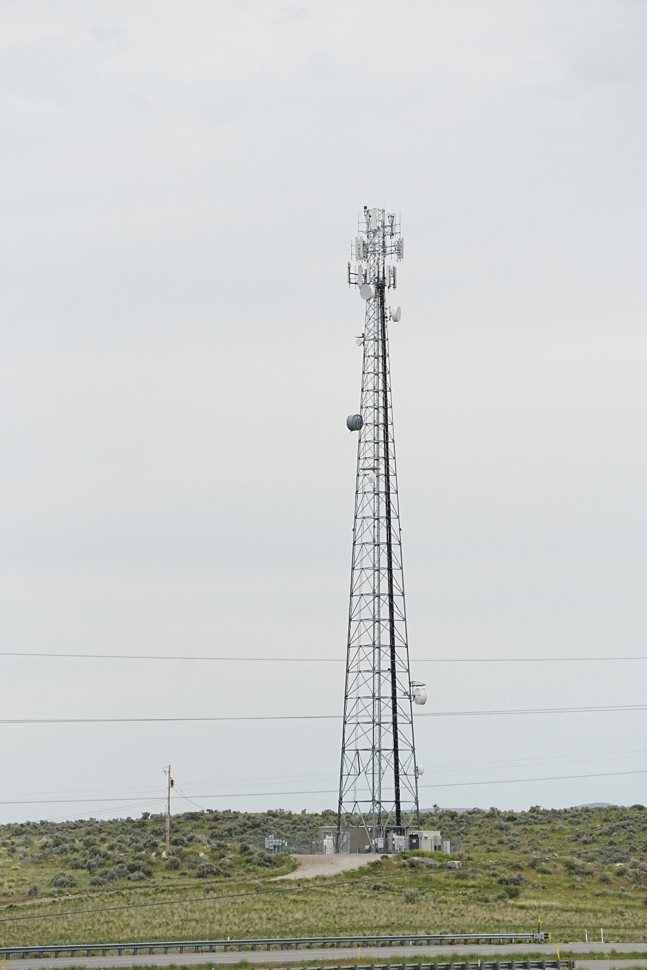 A tall tower with a variety of rectangular mobile network antennas and round microwave dishes.