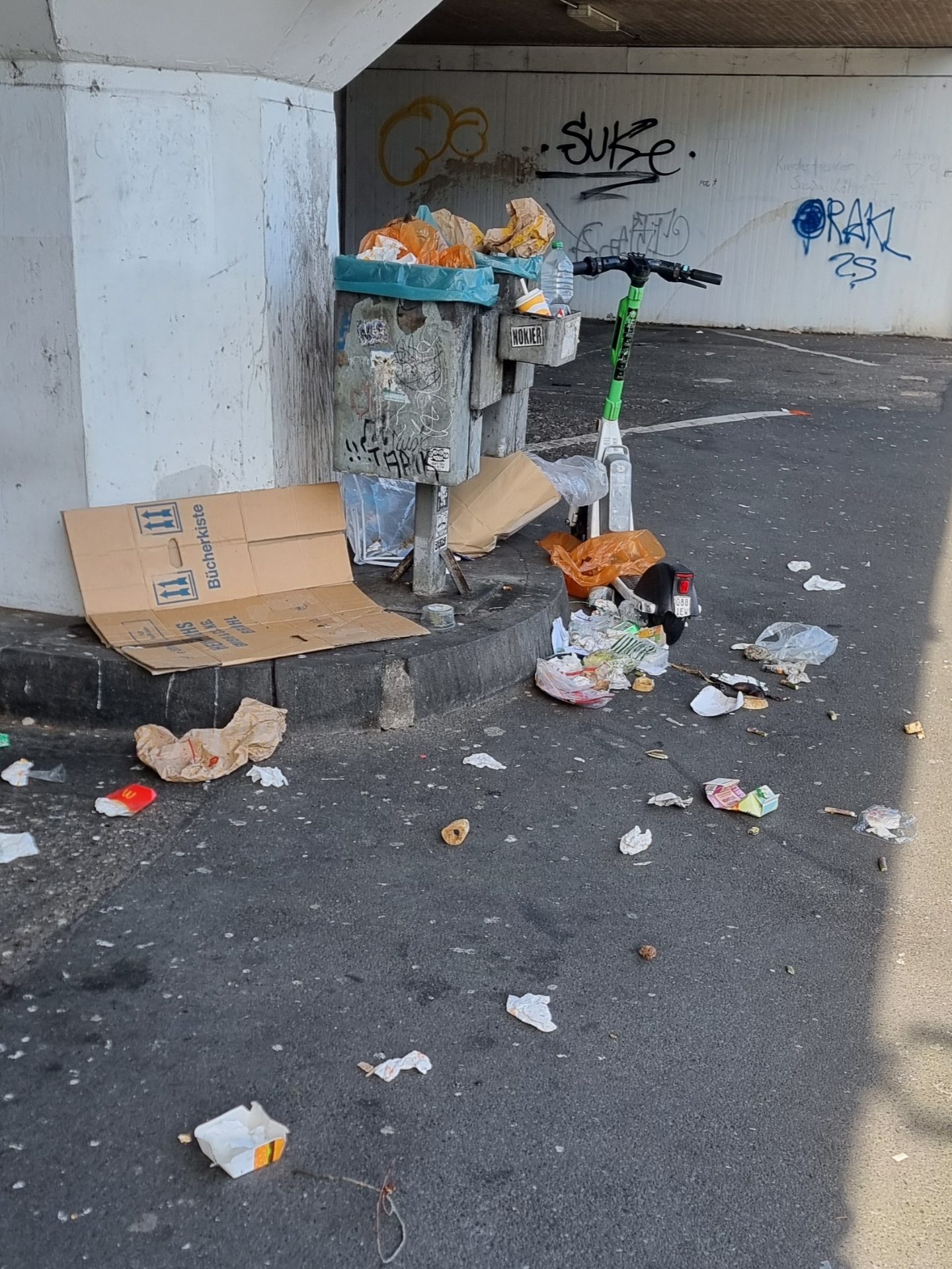 Überquillender Abfalleimer und wilder Müll auf dem Fußboden auf einem Parkplatz.