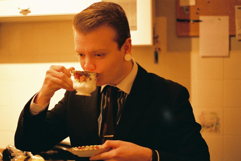 A well dressed person drinking tea from fine china