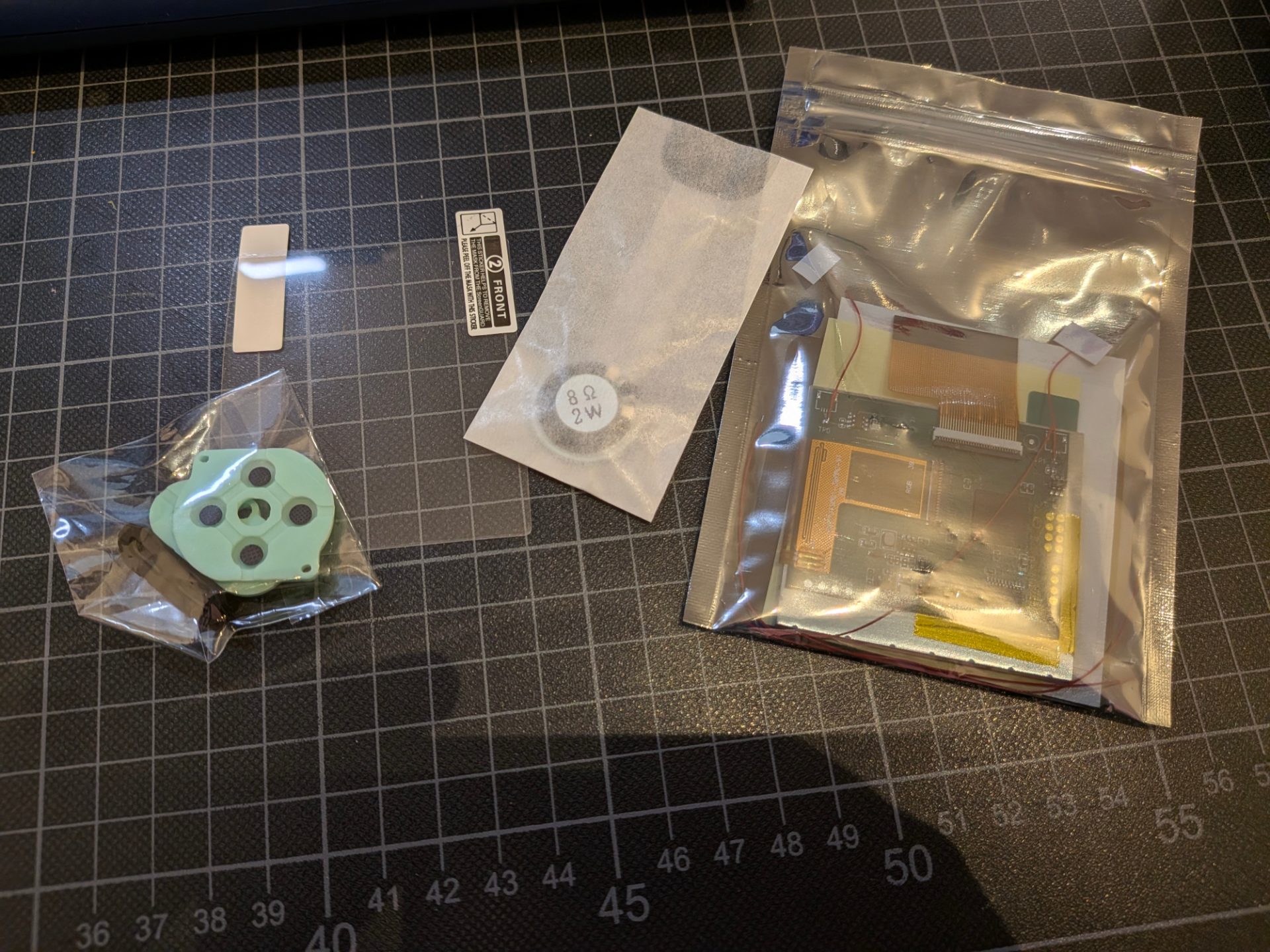 Individually sealed parts. Replacement pads for the buttons, a 2W speaker, and a screen in a static bag along with screen protector.