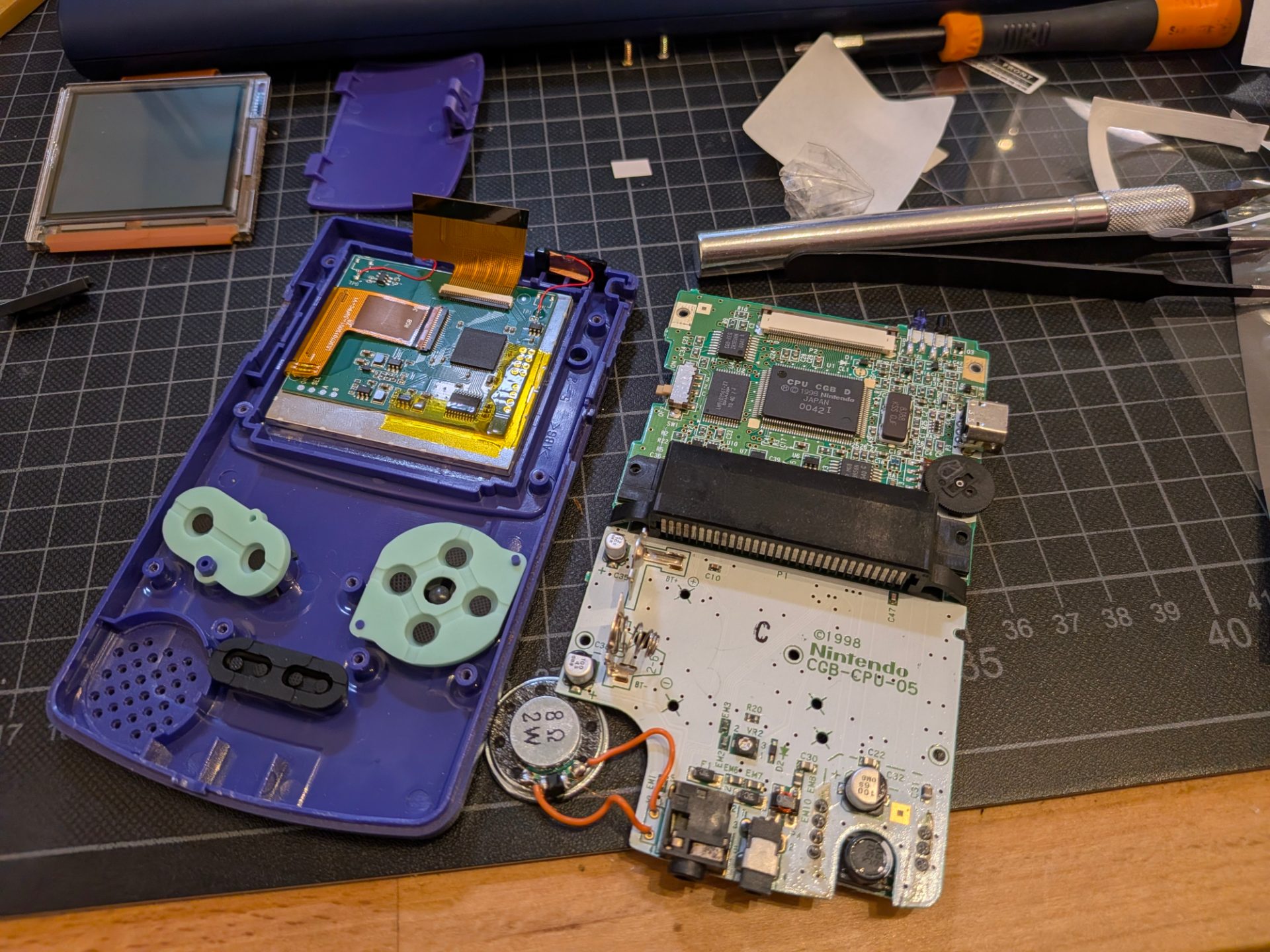 The new screen installed along with membrans and speaker, the circuit board sits to the right on the crafting mat.