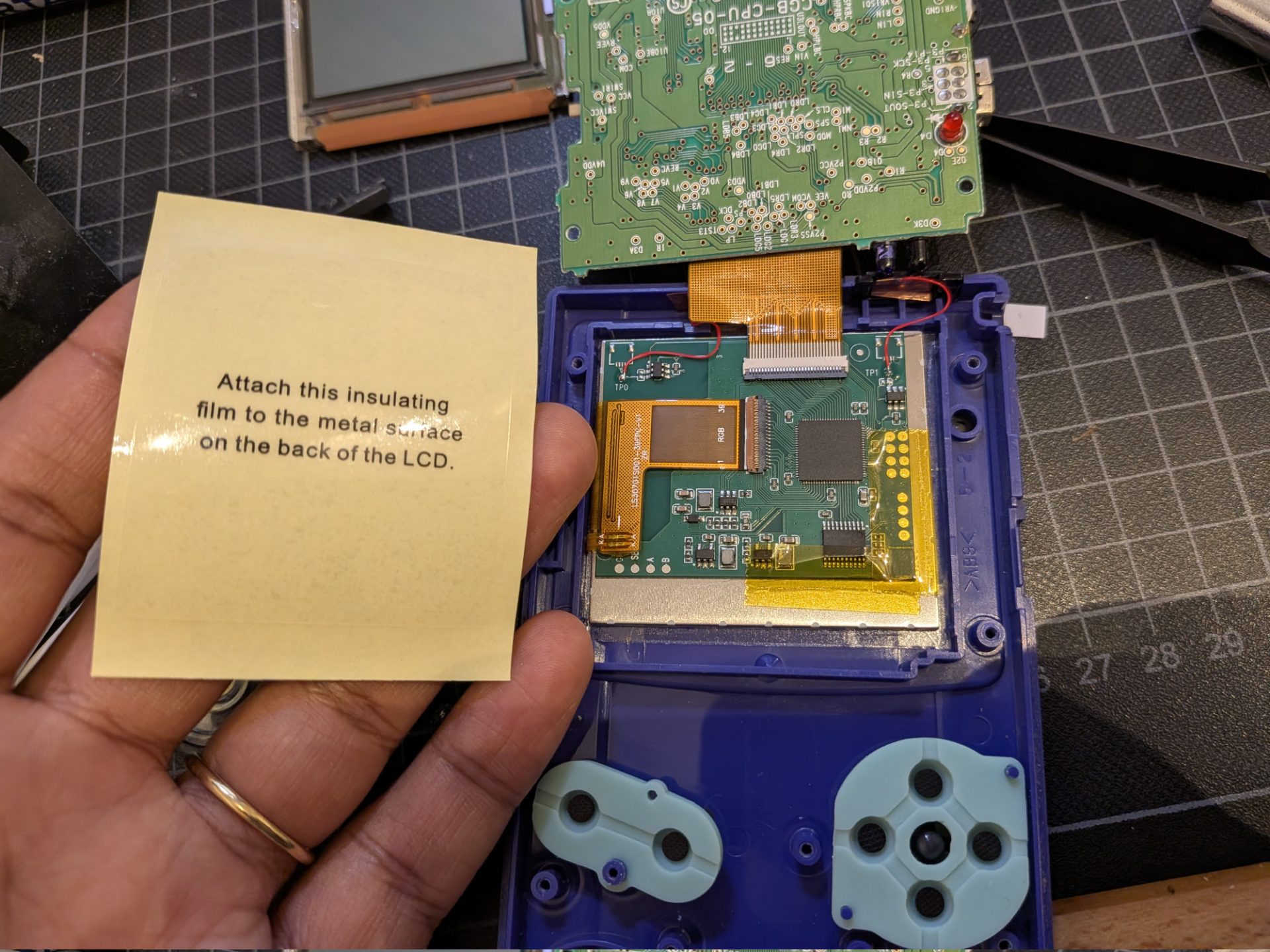 I'm holding a sticker that says "Attach this insulating film to the metal surface on the back of the LCD."