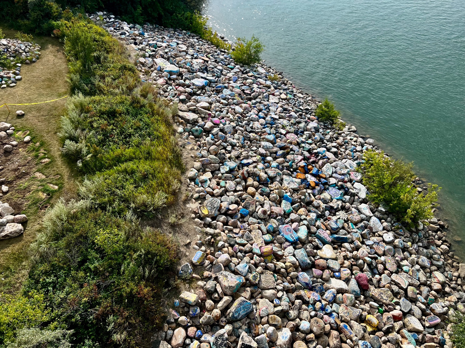 A photo of a river bed full of rocks with various colours painted on them