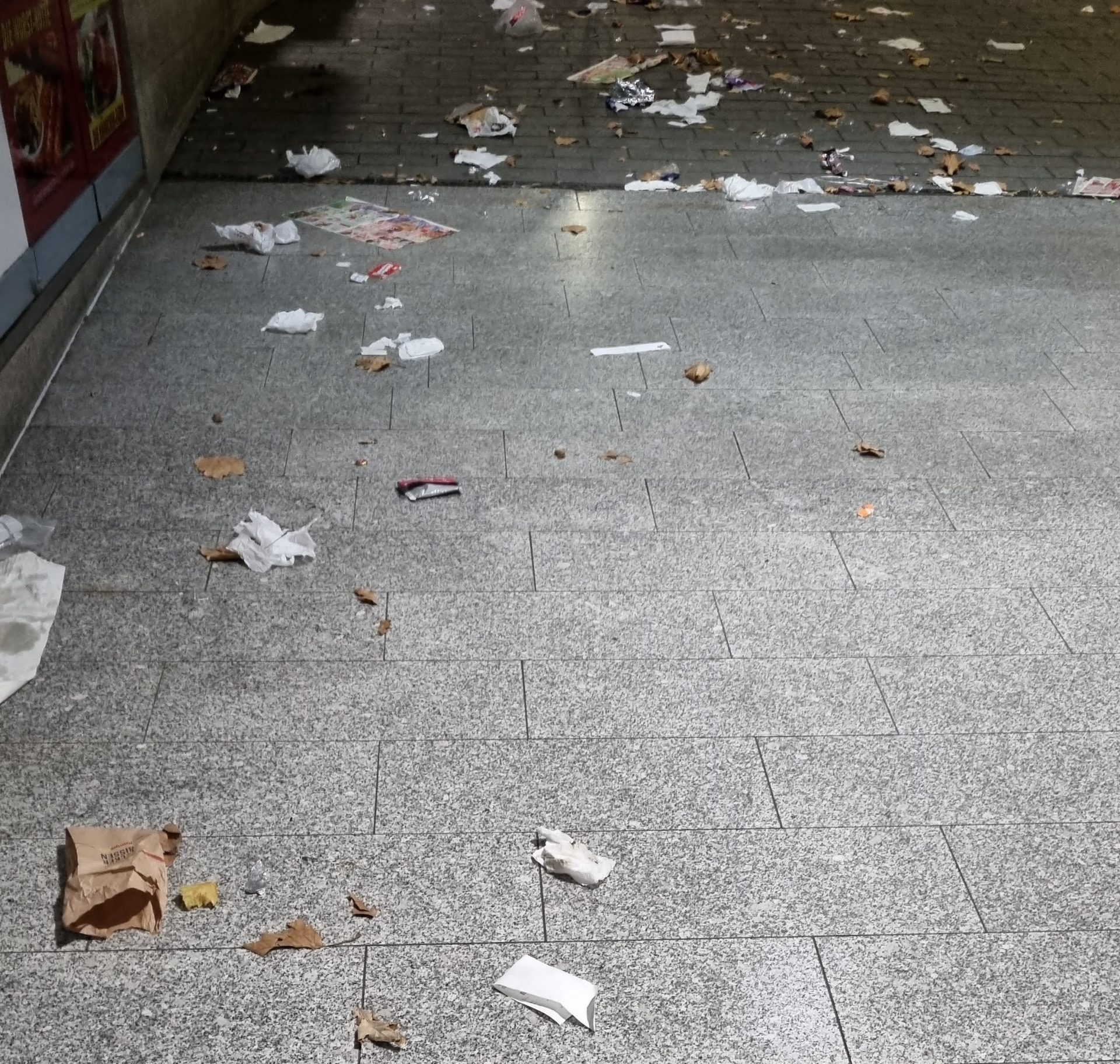 Müll auf dem Fußboden im Übergang von einem Platz in eine Einkaufspassage.