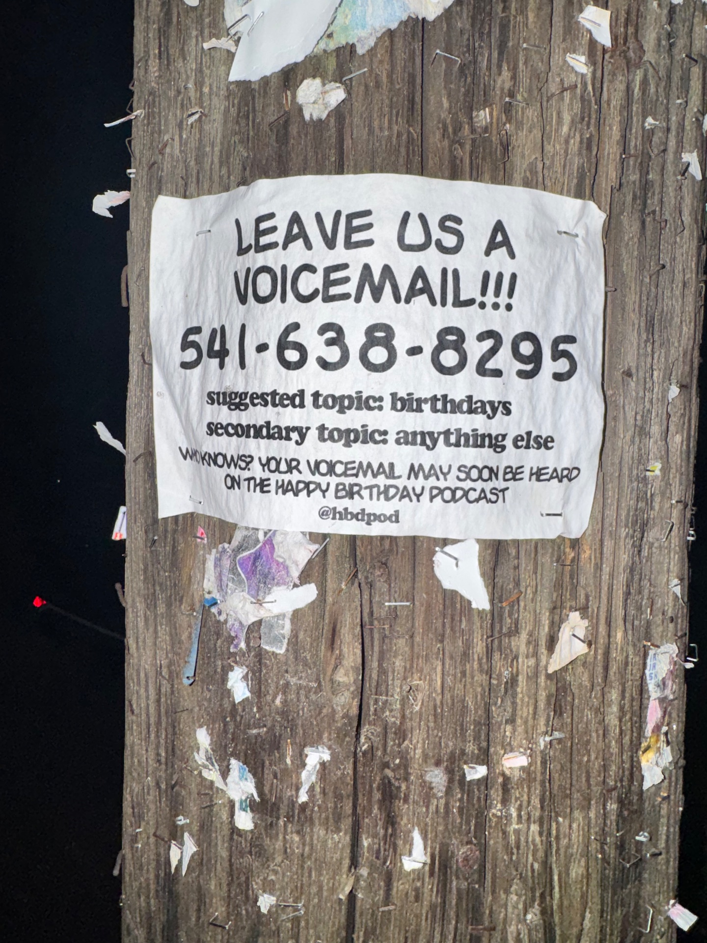 A telephone poll sign soliciting voicemails for a podcast