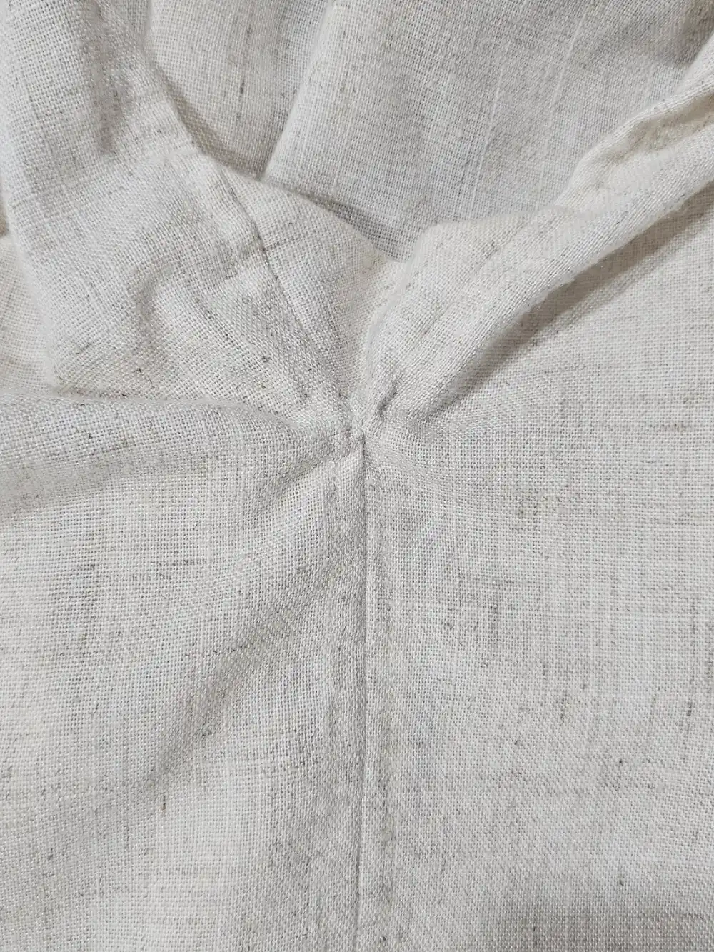 The outside of the side seam of the linen shirt, showing the gusset and top stitching.