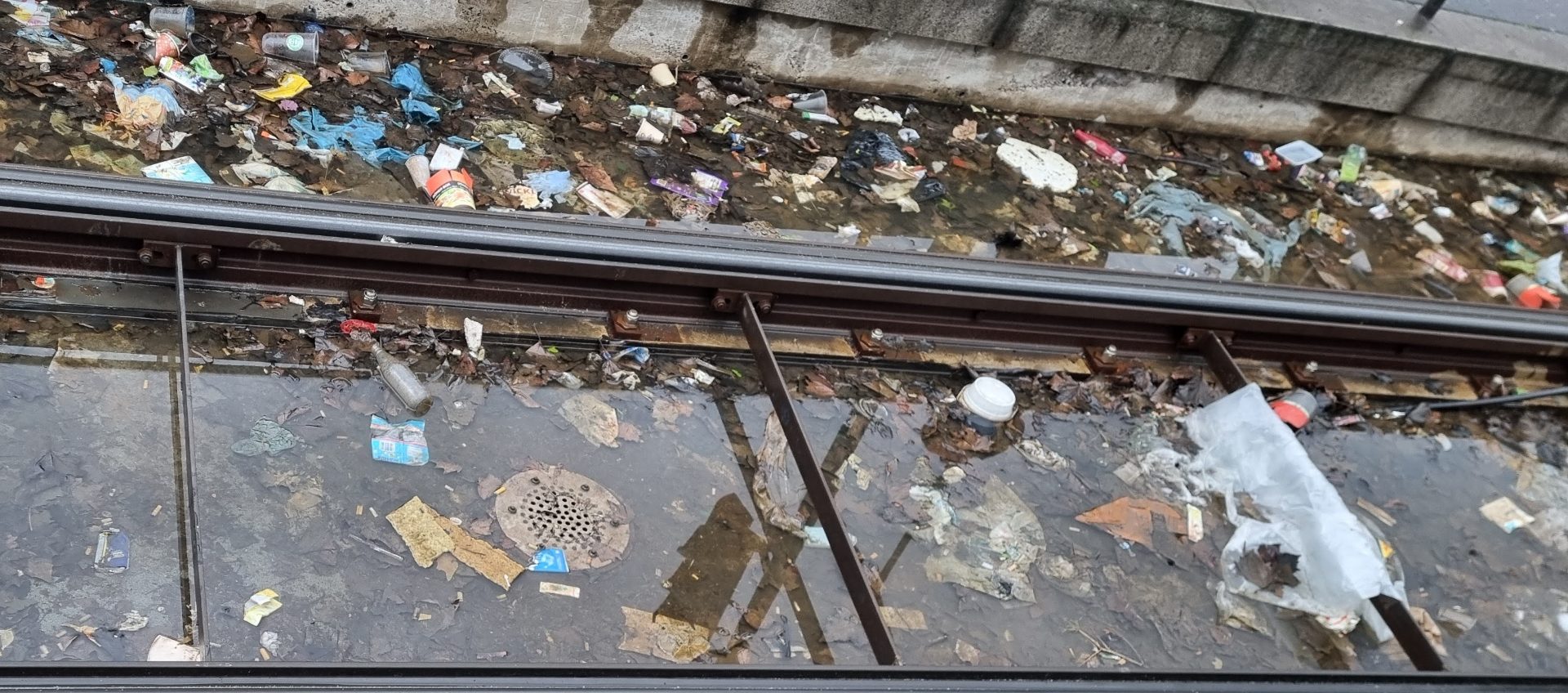 Verschiedene Abfälle im Gleisbett an einer Stadtbahnhaltestelle.