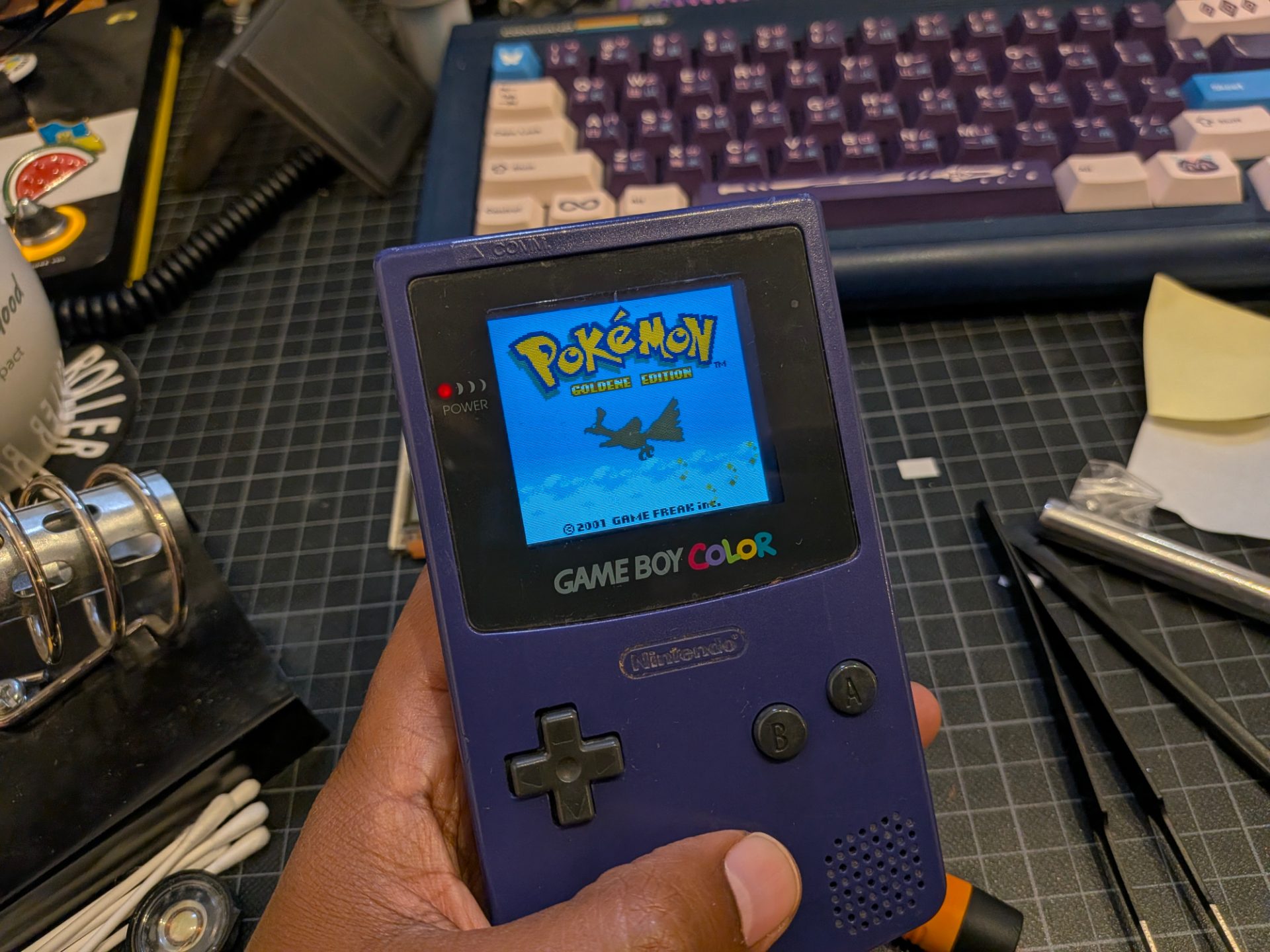 The Gameboy Color turned on showing the Pokemon Gold title screen with incredibly rich colors.
