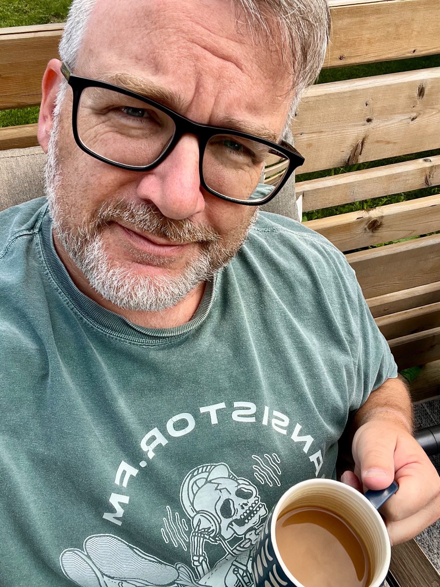 Me sitting with a coffee in hand looking at the camera, wearing a Transistor.fm t shirt
