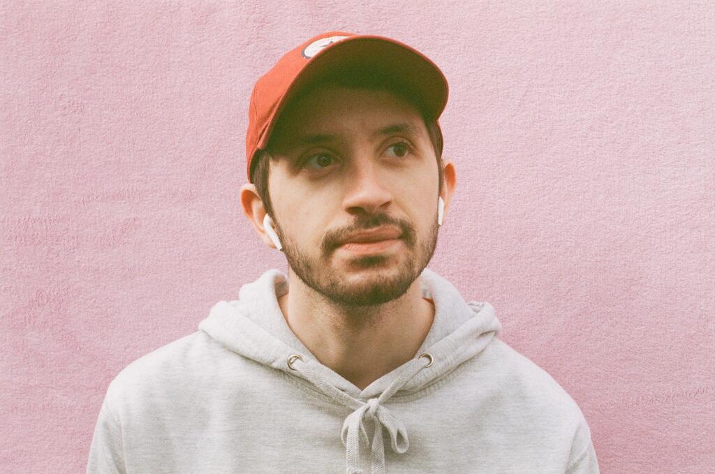 My brother standing in front of a pink background in a cap